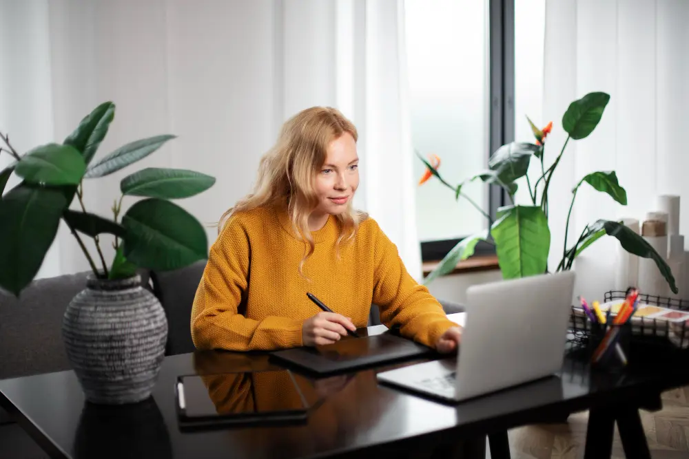 Femme souriante assise à son bureau devant son ordinateur